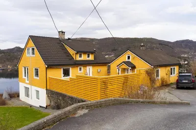 a yellow house with a large deck on the side of it at Small house close to nature and city in Bergen