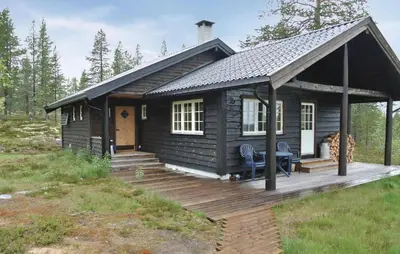 a log cabin with a deck and a table at Cozy Home In Rendalen With Sauna in Akrestrommen