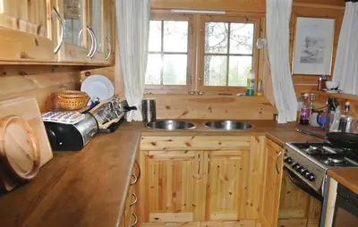 a kitchen with wooden cabinets and a sink and a stove at Cozy Home In Rendalen With Sauna in Akrestrommen