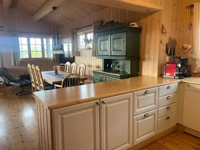 a kitchen with a counter and a dining room with a table at Koselig og sentral hytte med peis og badstue in Beitostøl