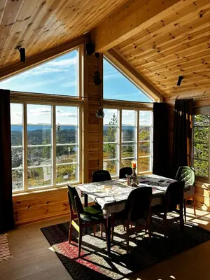 a dining room with a table and chairs and large windows at Mountain Cabin With Panoramic Views In Valdres in Etnedal