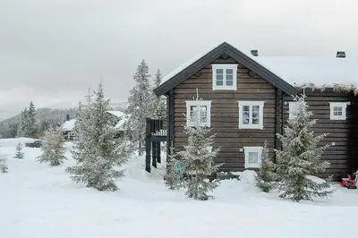 a log cabin in the snow with trees at Log Cabin By Mostertoppen Ski Stadium in Øyer