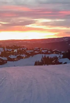 a view of a snowy mountain with a city in the background at Log Cabin By Mostertoppen Ski Stadium in Øyer