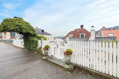 a white fence with two potted plants on it at Lysthuset den lille villa - authentic wodden house in Bergen
