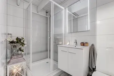 a white bathroom with a shower and a sink at Lysthuset den lille villa - authentic wodden house in Bergen