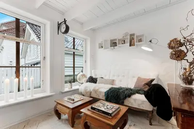 a living room with a white couch and two windows at Lysthuset den lille villa - authentic wodden house in Bergen