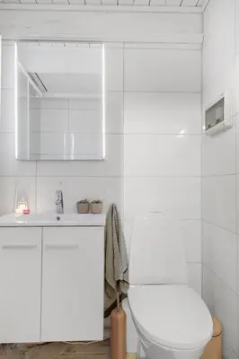 a white bathroom with a toilet and a sink at Lysthuset den lille villa - authentic wodden house in Bergen