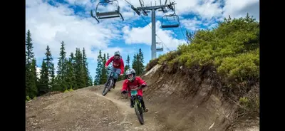 two people riding bikes on a dirt hill with a ski lift at Hafjell Ski-in Ski-Out in Øyer