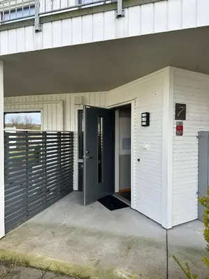 a white building with a door in front of it at Apartament Near Haugesund in Skred