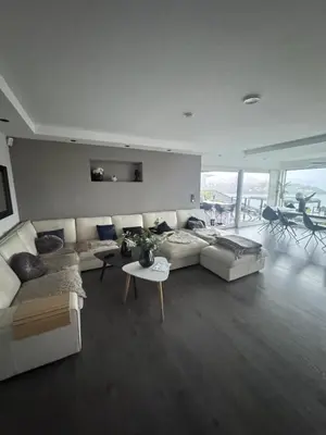 a living room with a white couch and a table at Villa med 5 soverom, 4 bad og 3 kjøkken, 400 m fra lokal badestrand in Bergen
