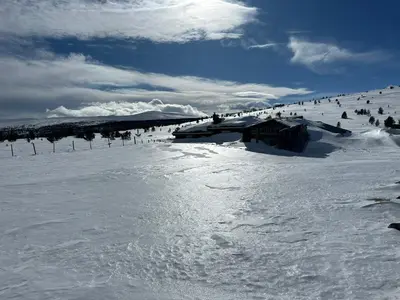 a snow covered slope with a ski lodge in the distance at Bottheimsætra