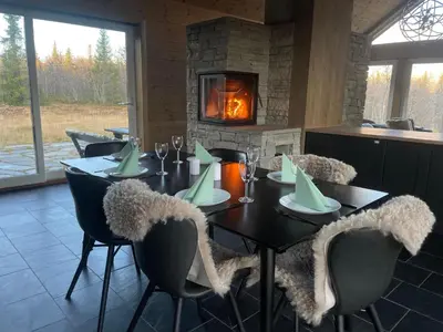 a dining room with a table and chairs and a fireplace at Moderne storhytte med 5 soverom og 3 bad in Beitostøl