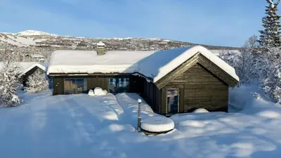 a house covered in snow with a pile of snow at Moderne storhytte med 5 soverom og 3 bad in Beitostøl