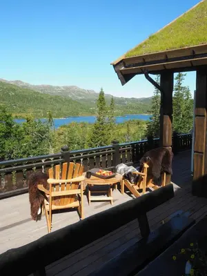 a deck with two wooden chairs and a table at Modern Mountain Cabin With A View Over The Sea