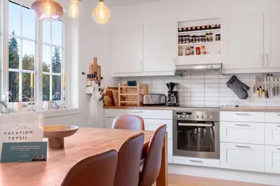 a kitchen with white cabinets and a wooden table with chairs at Fjellvangvegen 11 by Vacation Trysil in Trysil