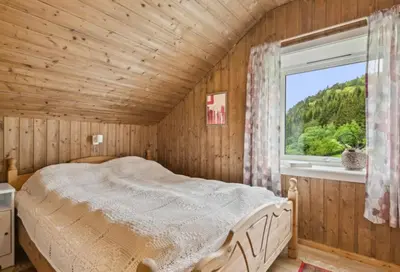 a bedroom with a bed in a wooden room with a window at Kvila in Tingvoll