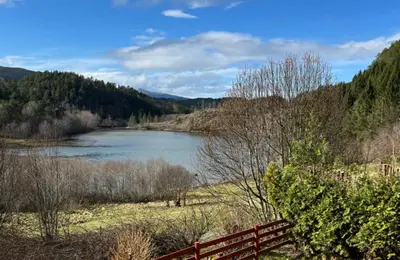 a river in a field with a red fence at Kvila in Tingvoll