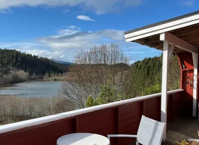 a porch with a chair and a view of a lake at Kvila in Tingvoll
