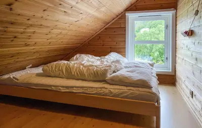 a bed in a wooden room with a window at Gorgeous Home In Leinøy With House Sea View in Fosnavåg