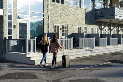 two women walking down a street with a suitcase at Vestnes Fjordhotell in Vestnes