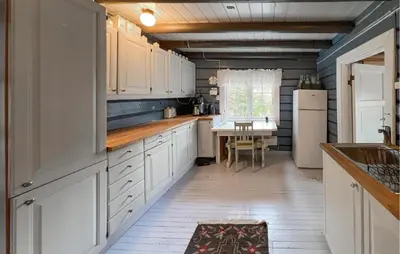 a kitchen with white cabinets and a table at 3 Bedroom Cozy Home In Mesnali in Mesnali
