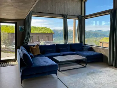 a living room with a blue couch and large windows at Modern Family Cabin By The Ski Trail In Tuddal in Tuddal