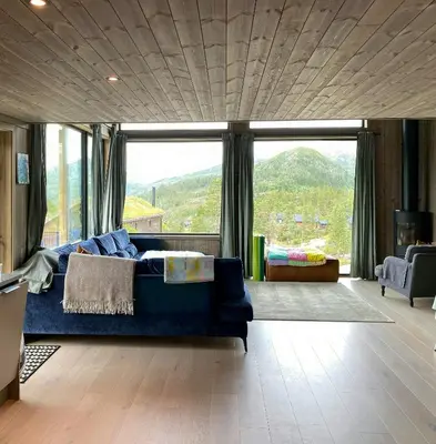 a living room with a blue couch and a large window at Modern Family Cabin By The Ski Trail In Tuddal in Tuddal