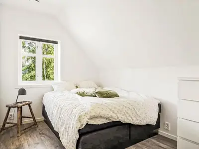 a bed in a white bedroom with a window at Holiday Home Holmen by Interhome in Strandebarm
