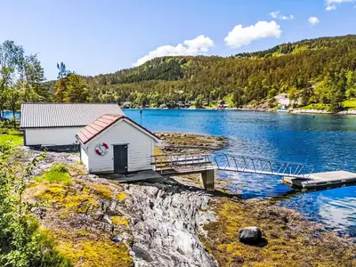 a small house on the shore of a lake at Holiday Home Holmen by Interhome in Strandebarm