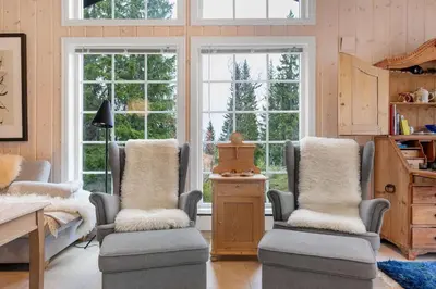 a living room with two chairs and a table and windows at Fagerasen 303 by Vacation Trysil in Trysil