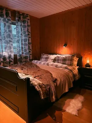 a bedroom with a bed with a wooden wall at Nikolaisens Nordic Panorama hideaway in Stranda