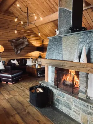 a living room with a fireplace in a log cabin at Cabin in Kvamskogen in Kvam