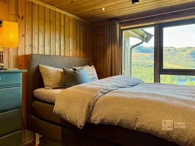 a bedroom with a bed and a large window at Modern cabin with panoramic view, sauna and fire pit in Espedalen