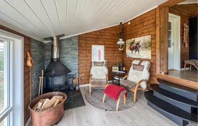 a room with a fireplace and chairs and a table at Amazing Home In Sjusjøen With Sauna in Sjusjøen