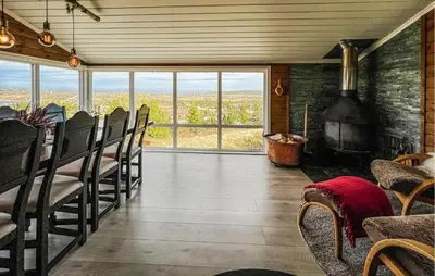 a living room with a table and chairs and a fireplace at Amazing Home In Sjusjøen With Sauna in Sjusjøen