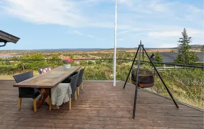 a wooden table and chairs on a deck with a view at Amazing Home In Sjusjøen With Sauna in Sjusjøen