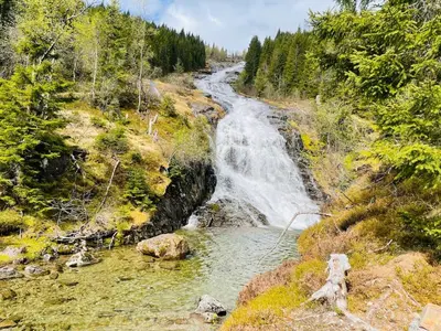 a waterfall on the side of a hill with a river at JOlster apartaments - lake view in Årdal