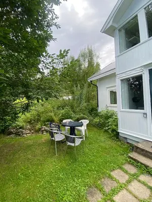 a table and chairs in a yard next to a house at Cosy farmhouse with spa as add on service in Gjøvik