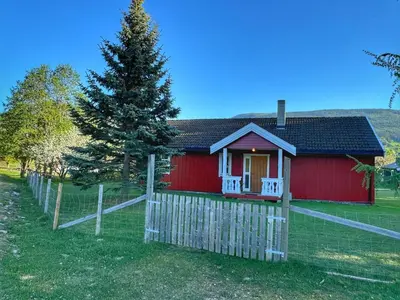 a red house with a fence and a tree at Det vesle huset på Lysåker in Nord-Fron