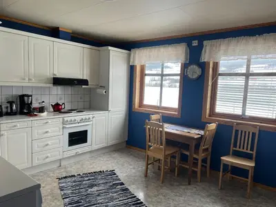 a kitchen with white cabinets and a table and chairs at Det vesle huset på Lysåker in Nord-Fron