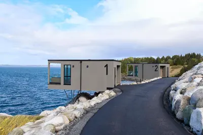 a house on the shore of a body of water at Hideaway Herdla luxurious cabins 15 m above the sea in Herlø
