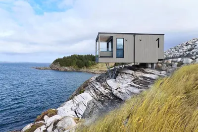a modern house on a cliff near the water at Hideaway Herdla luxurious cabins 15 m above the sea in Herlø