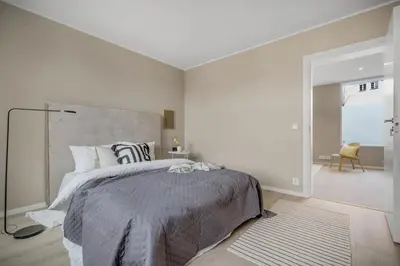a white bedroom with a large bed and a chair at Beautiful 3 room apartment centrally located in Sandviken in Bergen