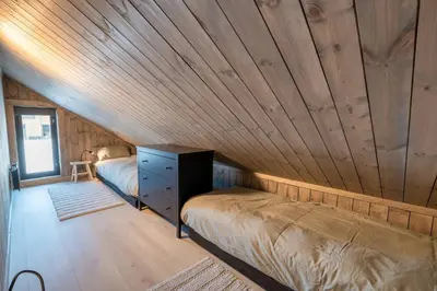 a room with two beds and a wooden ceiling at Cozy Family Cabin Ski centre, shuttle bus in Noresund
