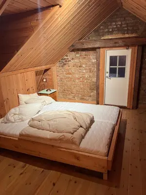 a bedroom with a large bed in a attic at Fengselet Gjestegård in Leira