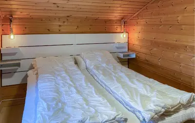 a bed in a room with a wooden wall at 4 Bedroom Lovely Home In Leinøya in Fosnavåg