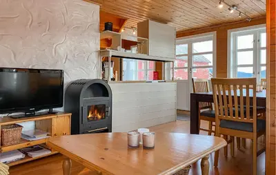 a living room with a fireplace and a table with a tv at 4 Bedroom Lovely Home In Leinøya in Fosnavåg