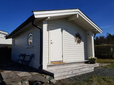 a small white shed with a porch and a door at Et golfslag fra Stiklestad Golfklubb in Verdal