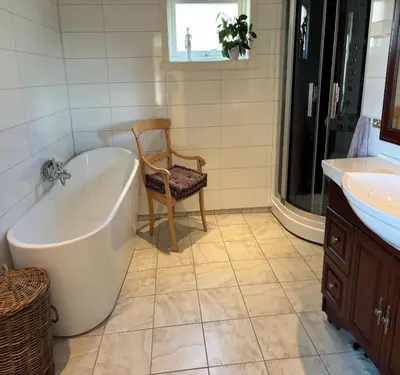 a bathroom with a tub and a chair next to a sink at Jåstad Gjestetun in Jåstad