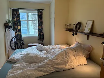 an unmade bed in a bedroom with a window at Jåstad Gjestetun in Jåstad